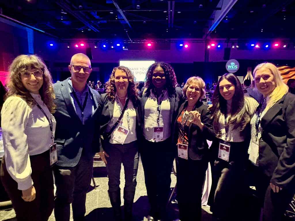 Group of people posing together at a conference or networking event with stage lighting in the background.
