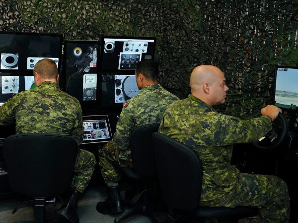 Canadian Armed Forces members operating simulation equipment at a control station.